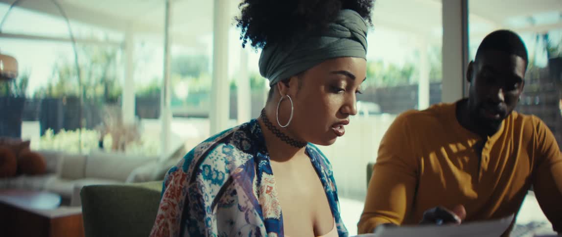 A young Black couple collaborates on their finances, high-fiving in agreement while sitting at their dining table