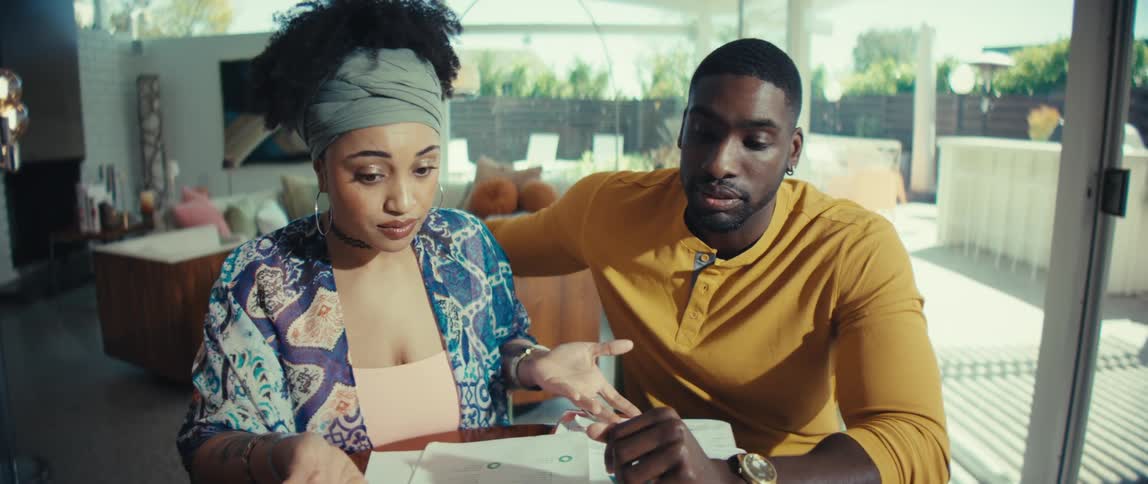 A young African American couple has a serious discussion while reviewing their finances and budget at the dining table in their modern home