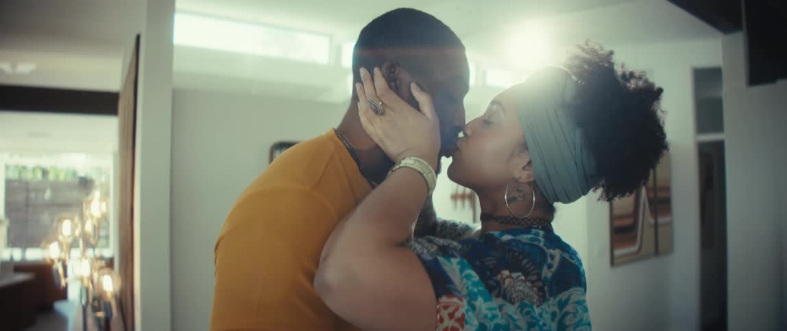 A joyful African American couple dances romantically and shares an intimate kiss in their sunlit home in slow motion