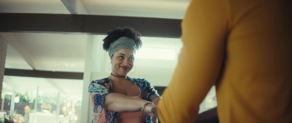A smiling woman is led by the hand and dances joyfully with her partner in their sunlit modern home