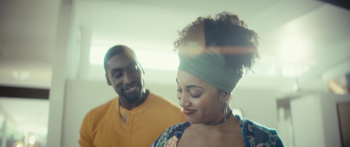 An affectionate young Black man embraces his beautiful girlfriend from behind as they share a happy moment at home