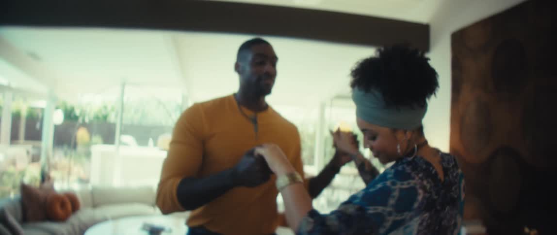 A loving young couple dances together in slow motion in their bright and modern living room