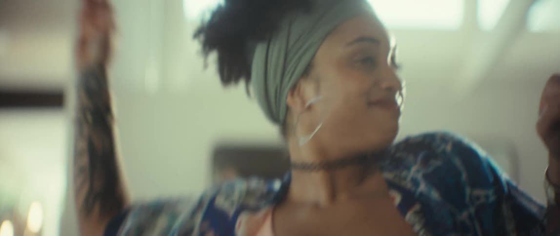 A carefree and stylish young woman laughs and dances with joy in a sunlit room in slow motion