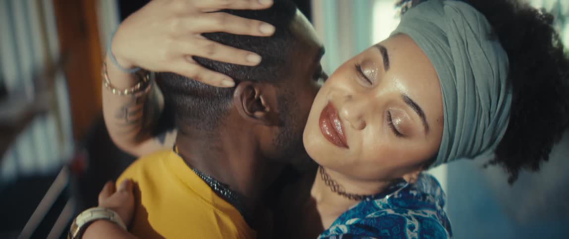 A loving Black couple shares an intimate and sensual slow-motion moment as the man kisses the woman's neck before they tenderly kiss