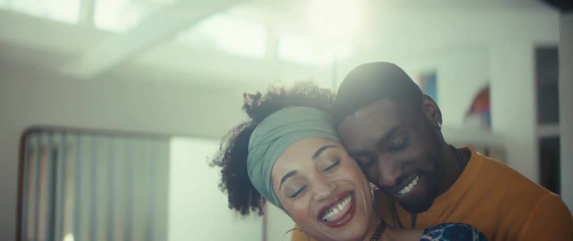 An intimate slow-motion shot of a beautiful couple laughing and dancing together in their sunlit home