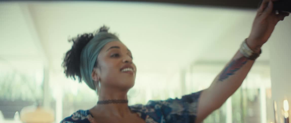 A young, stylish couple dances together in slow motion, starting from their feet and tilting up to reveal their loving embrace in a bright, modern home