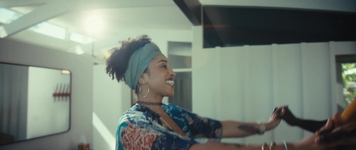 A happy Black couple holds hands and dances together in slow motion inside their sunlit, modern home