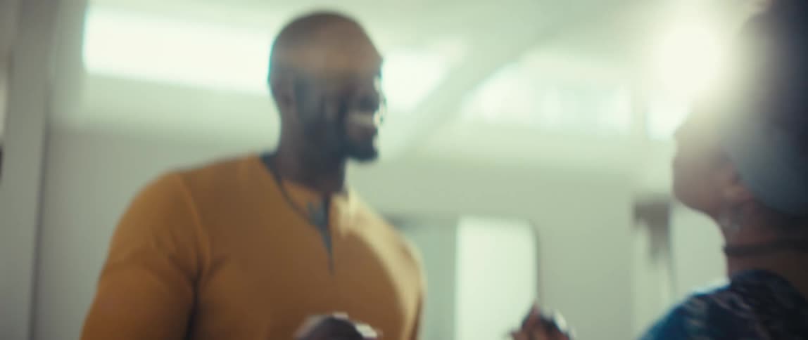 A smiling Black couple laugh and dance together in slow motion in their bright modern home