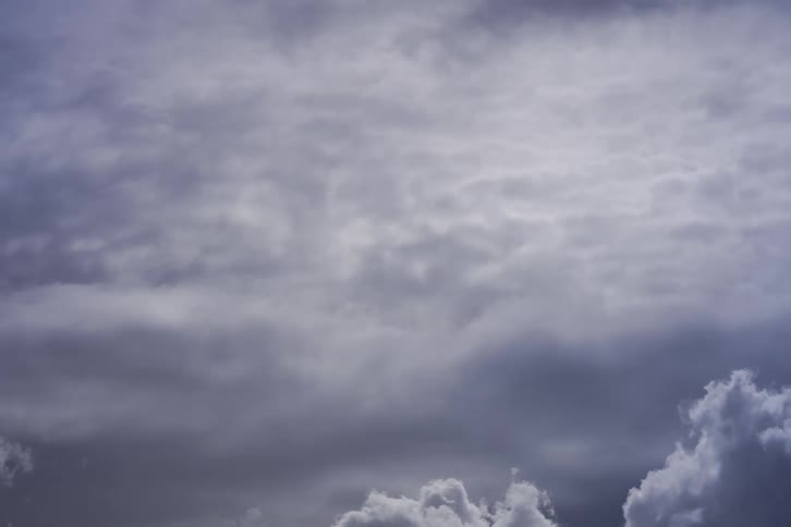A dramatic time-lapse shows a large grey cloud slowly dissipating into an overcast sky