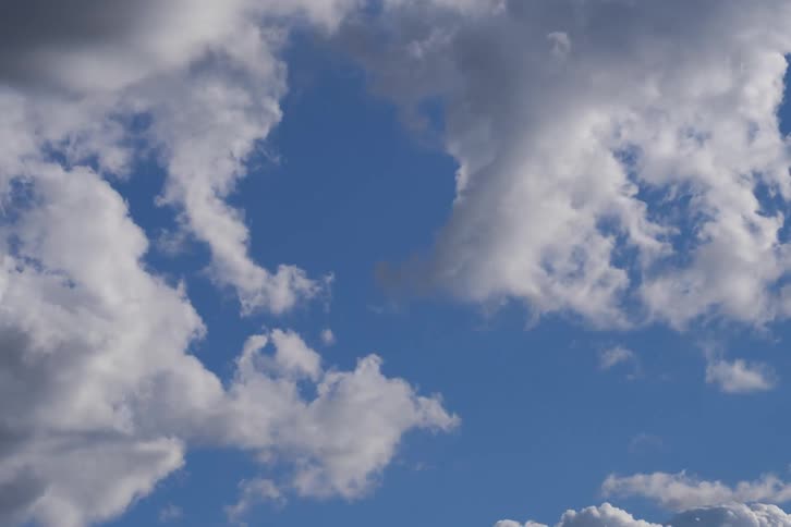 A calming time-lapse captures the movement of white cumulus clouds across a vibrant blue sky