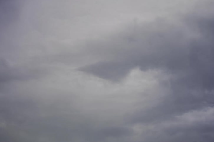 Dark storm clouds slowly drift across a dreary, overcast sky