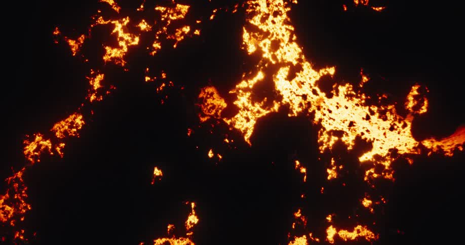 A mesmerizing top-down aerial shot shows glowing molten lava flowing at night