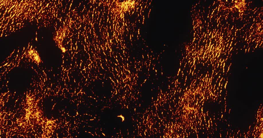 An abstract, fiery texture slowly burns and spreads across a dark surface, resembling glowing embers