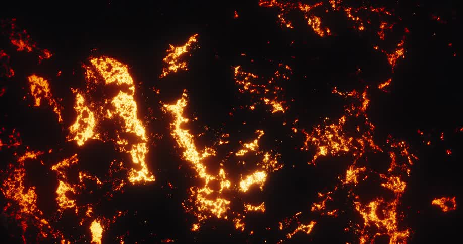 Aerial top-down view reveals the raw power of nature as a volcanic lava field glows intensely against the dark night