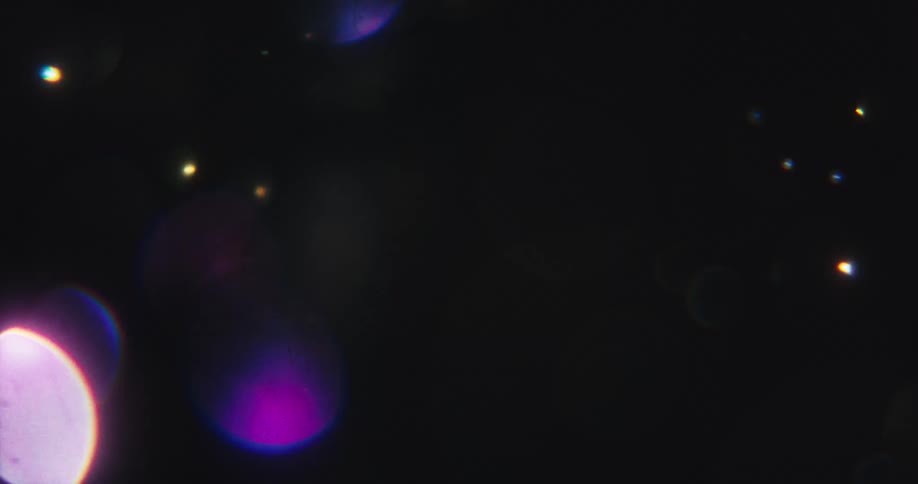 Abstract, colorful bokeh light orbs float and shimmer against a dark background, creating a dreamy and ethereal atmosphere