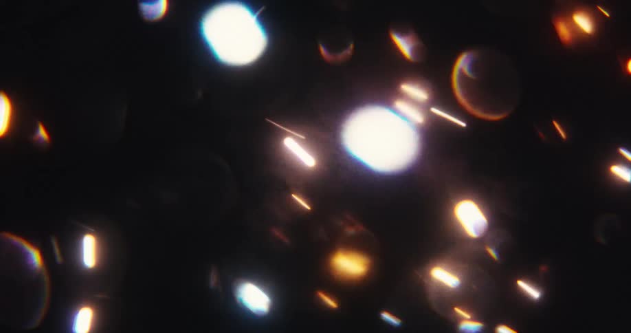 Abstract background of glowing bokeh particles and shimmering light streaks floating in darkness