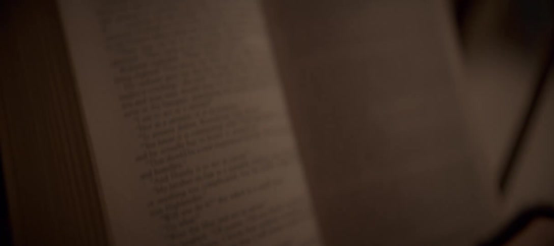 An extreme close-up slowly focuses on an open book's pages, revealing the text in a warm, intimate setting