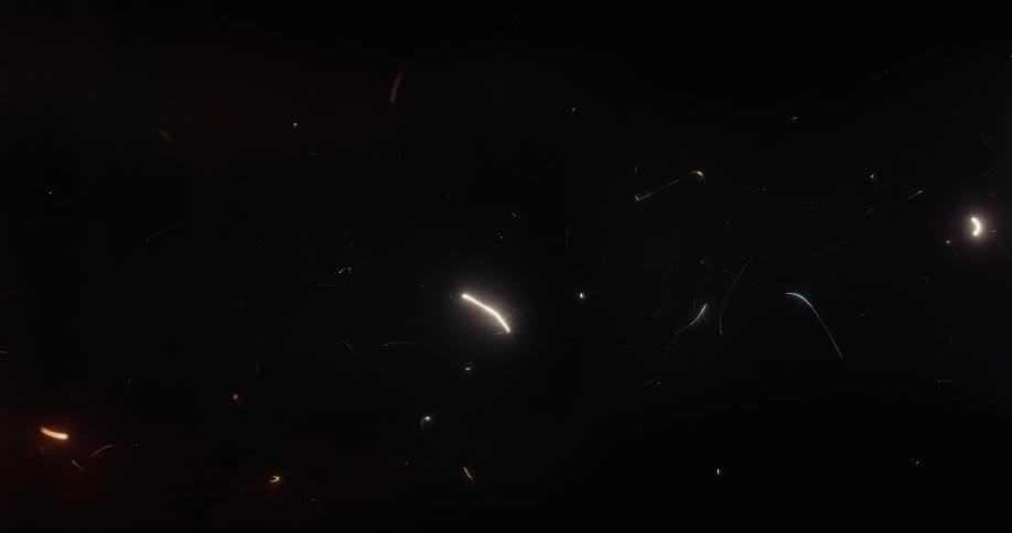 An abstract animation of colorful glowing particles and light trails moving chaotically on a black background