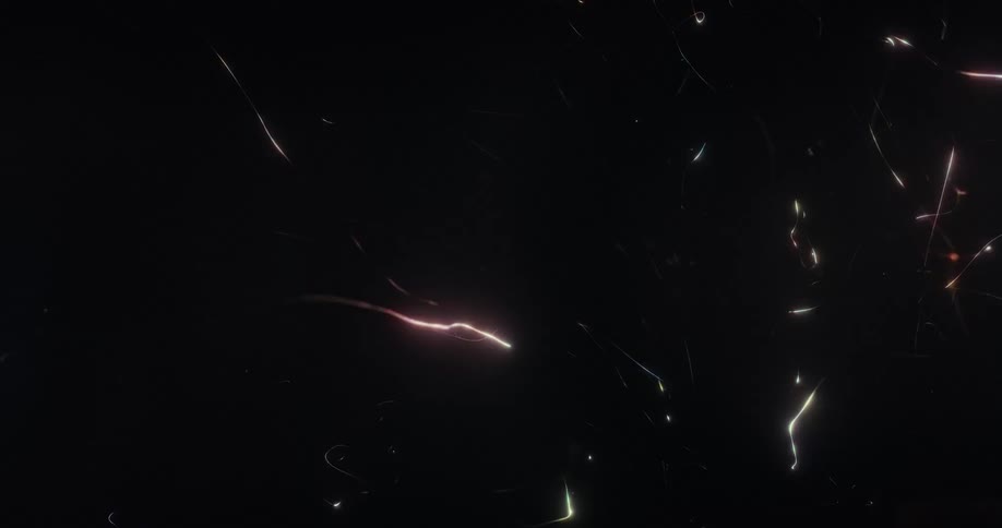 A dynamic and abstract animation of colorful glowing particles and light trails moving chaotically on a black background