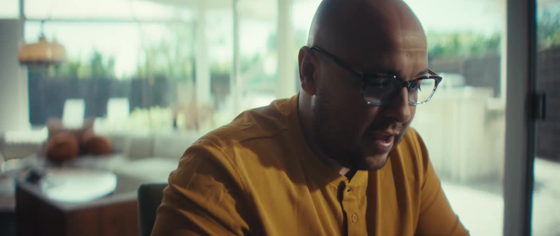 Close up of a businessman in glasses talking on a video conference call from his modern, sunlit home