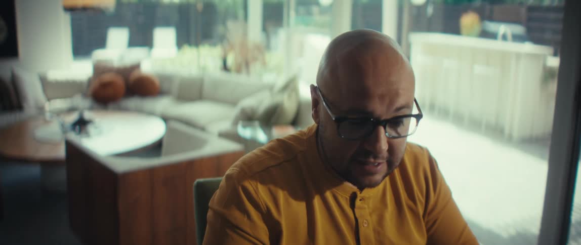 A businessman working from his home office passionately makes a point during a video conference call, with the camera slowly zooming in on his face