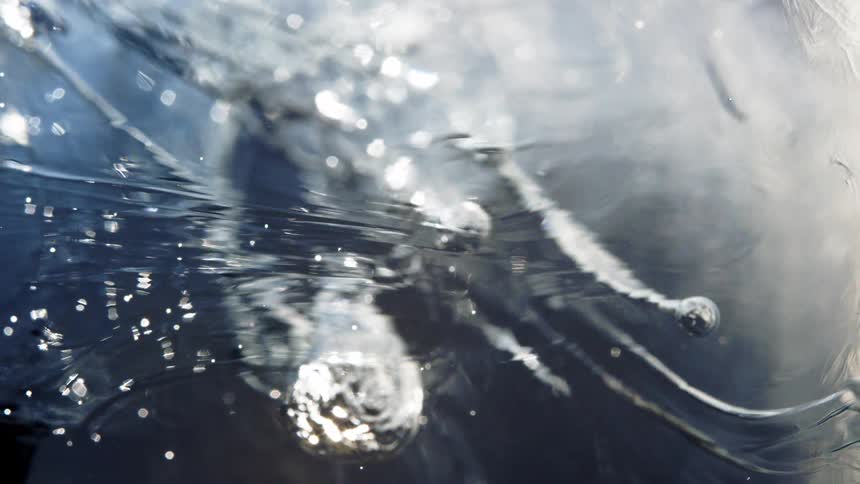 An extreme close-up shot of shimmering air bubbles trapped within slowly melting ice