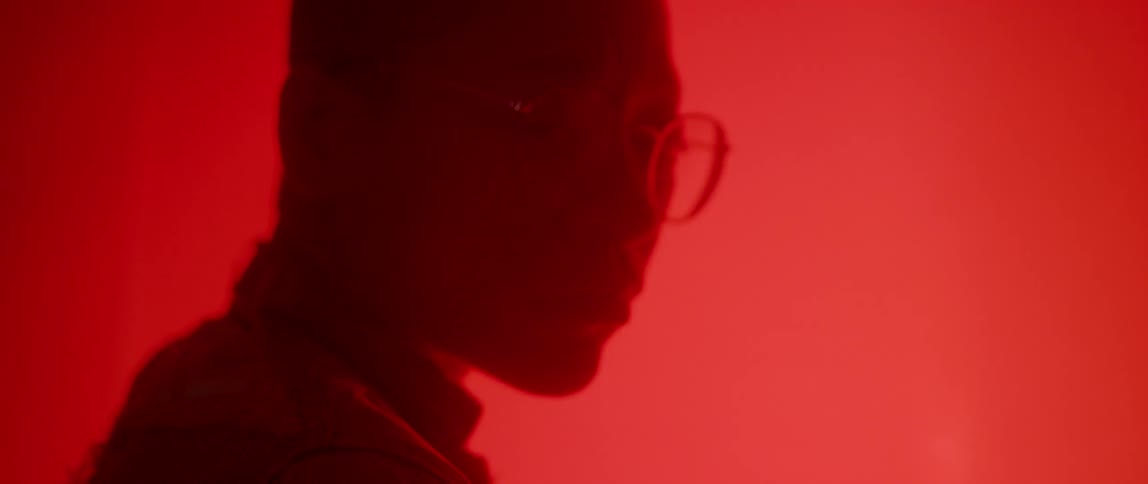 A person stands with red lights glowing all around