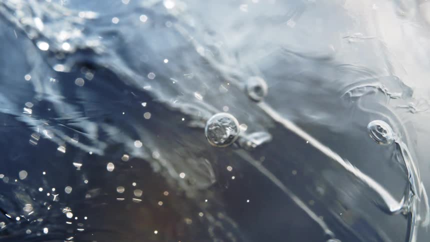A macro close-up of glistening ice slowly thawing, revealing intricate frozen patterns and trapped air bubbles