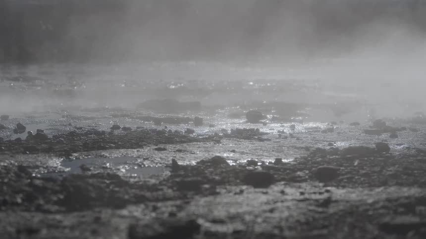 Close up of steam rising from the misty, rocky ground of a geothermal hot spring