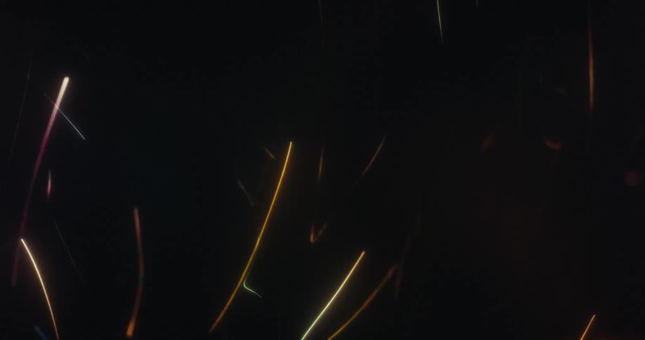 Abstract colorful light streaks and sparks dance and swirl energetically on a dark background