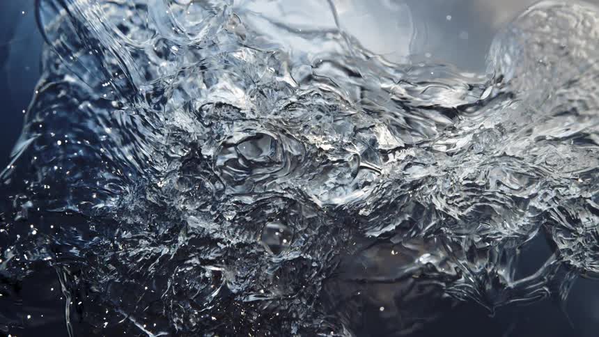 An abstract close-up of water freezing into solid ice with shimmering light reflections