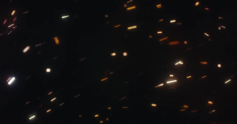 Abstract colorful light particles and embers streak across a dark background