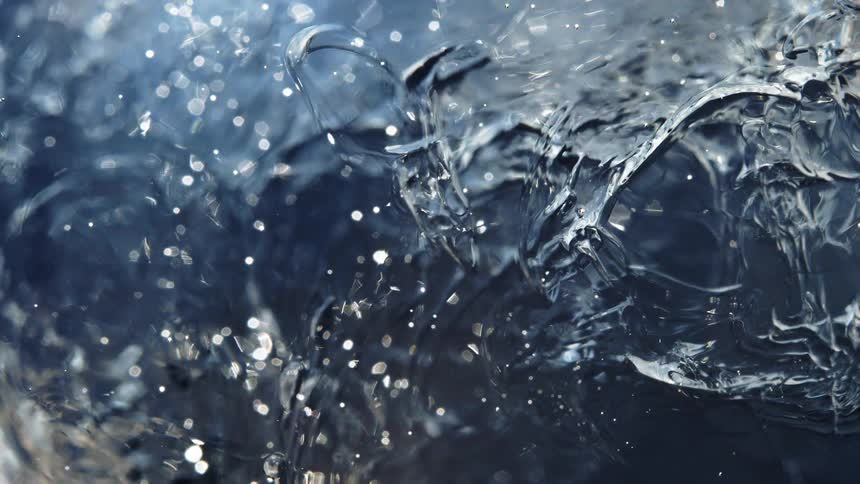 A shimmering blue liquid surface glitters with bokeh highlights in an abstract macro view