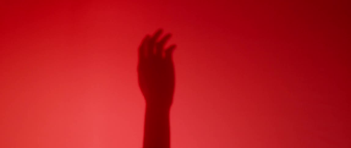 A person outstretches their hands with a red glow all around