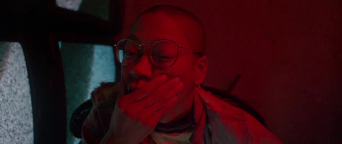 A person wearing glasses wipes their face