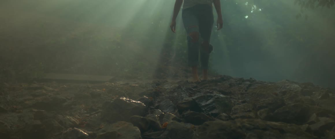 The water rushes over the rocks past a woman walking