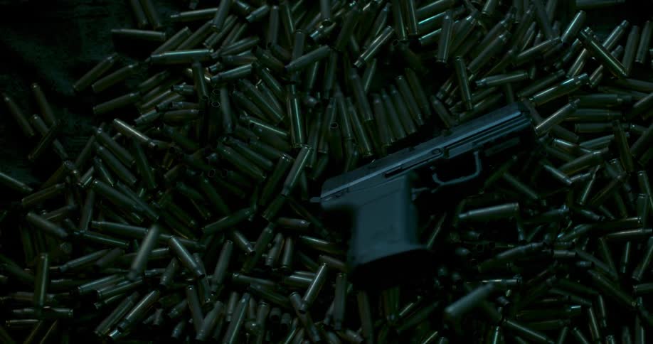 A handgun landing into a large pile of shell casings