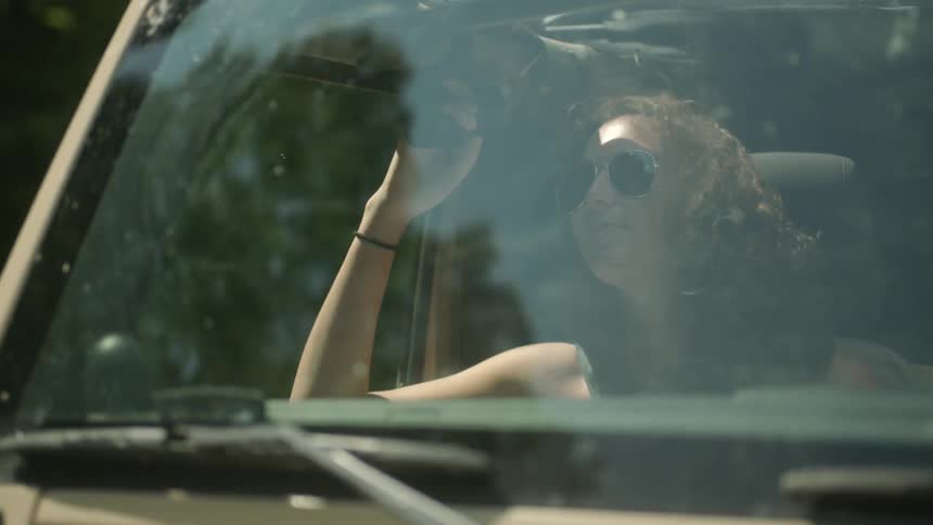 Woman riding in a car wearing sunglasses