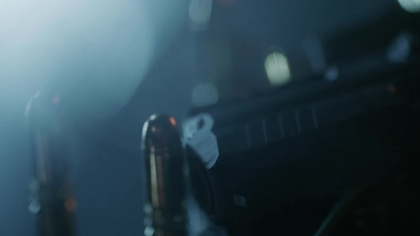 Smoke swirls around a gun and bullets on a reflective surface