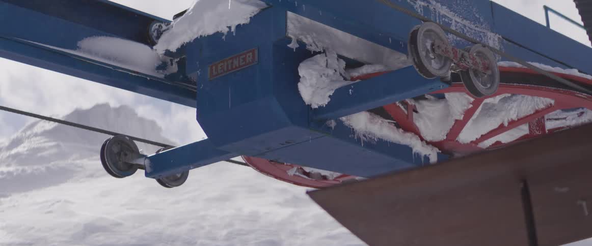 The turning wheels and pulleys of a snow-covered Leitner ski lift transport system on a cold winter day
