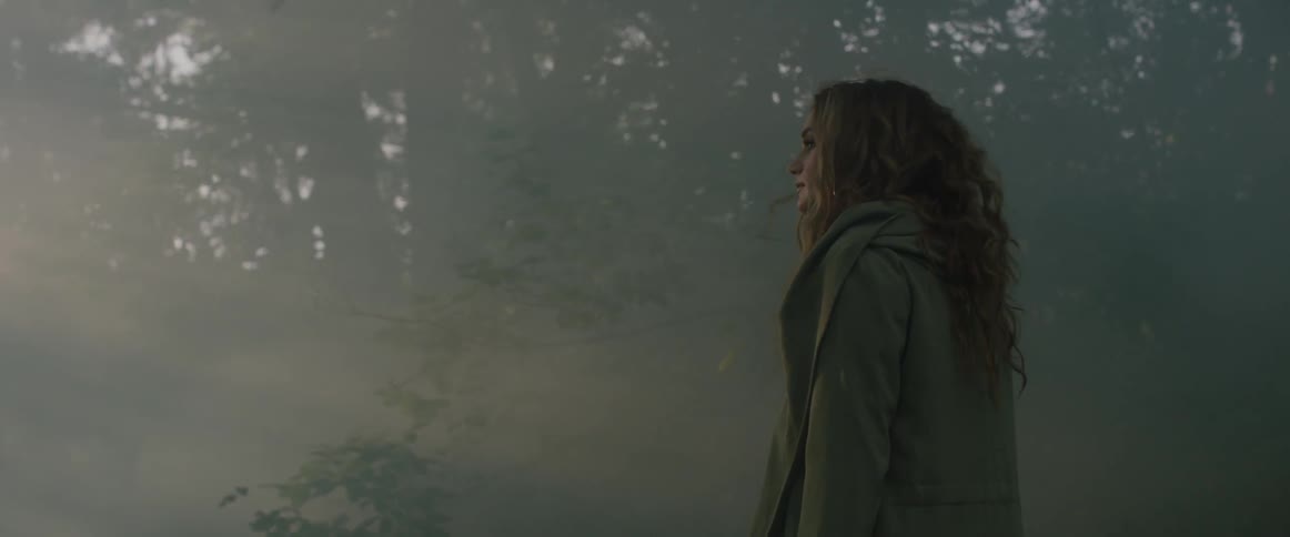 A woman walks through a foggy forest