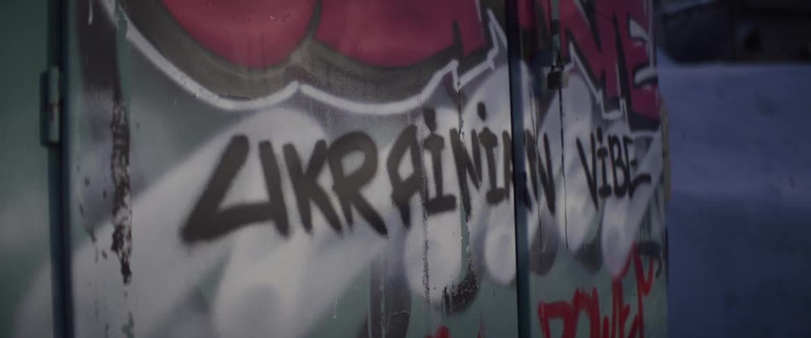 A close-up of 'Ukrainian Vibe' graffiti spray-painted on a weathered urban wall