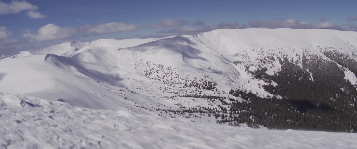 A breathtaking panoramic view of a snow-covered mountain range under a clear blue sky on a sunny winter day