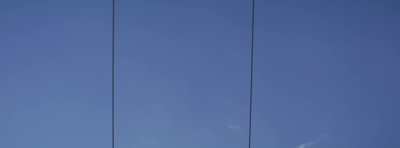 Close up of empty ski lift chairs moving continuously up a mountain against a solid blue sky
