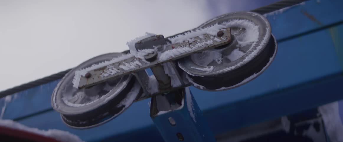 A close-up of a frosted pulley on a ski lift spinning during a cold winter day