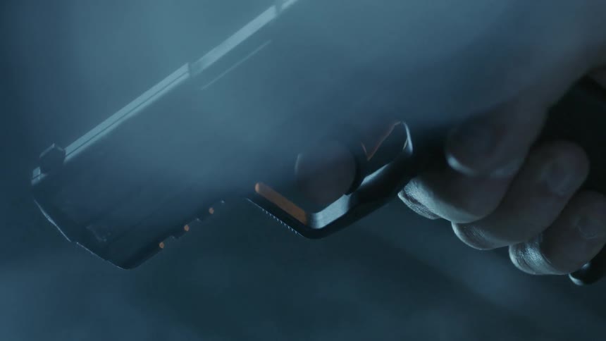 Person picks up a gun from table full of bullets