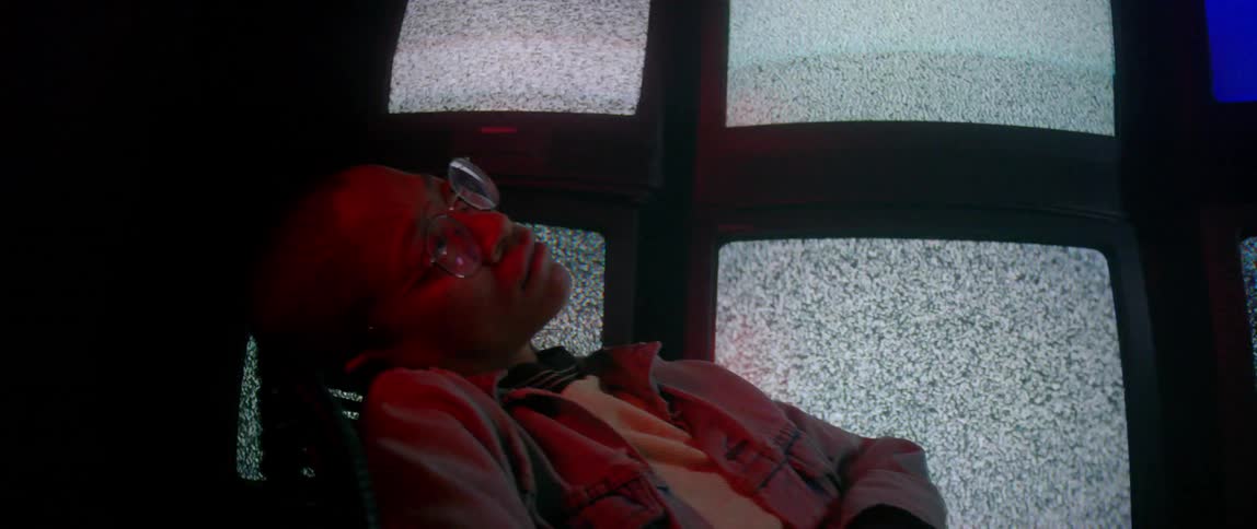 A person sleeping in a chair next to many static screens