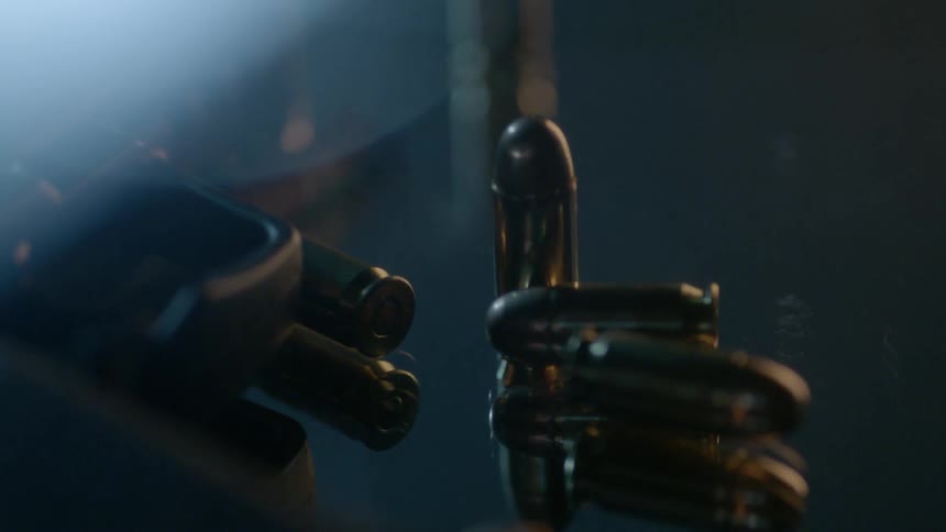 Bullets and a gun line a dark counter
