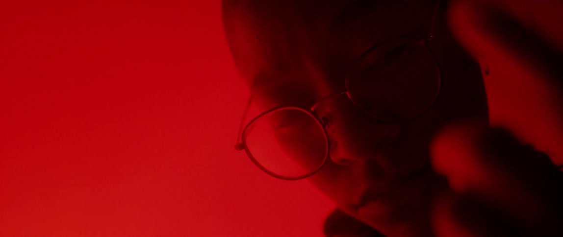 A person wearing glasses is in a red room