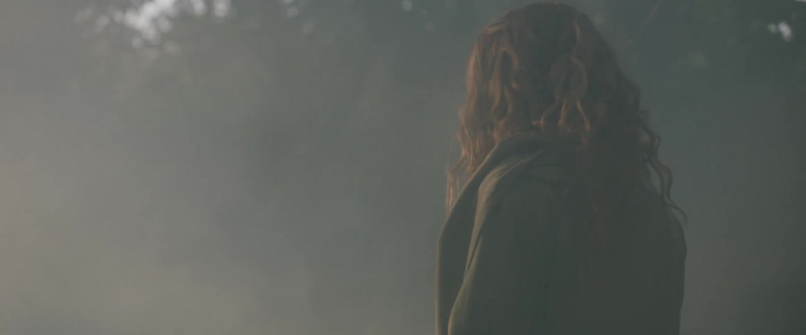 A woman is walking in a misty natural landscape